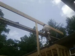 Carpenter setting a ridge beam over a new addition frame — Ice Dam Removal by Roofing Brothers in Cheraw