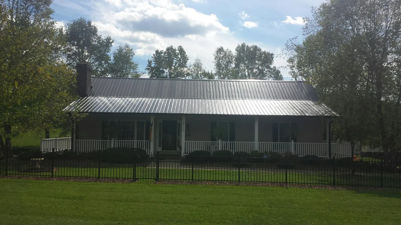 Gray metal roof on a brick ranch with a full width front porch — Gutter Guard Installation work by our crew in Cheraw